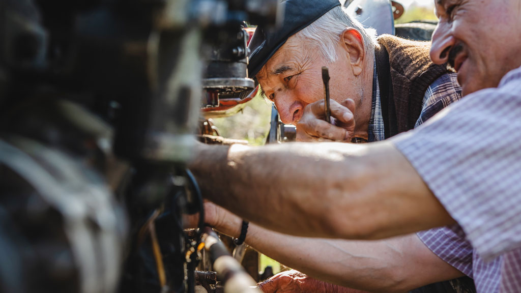 Agriculteur inspectant son tracteur ancien dans une cour de ferme française